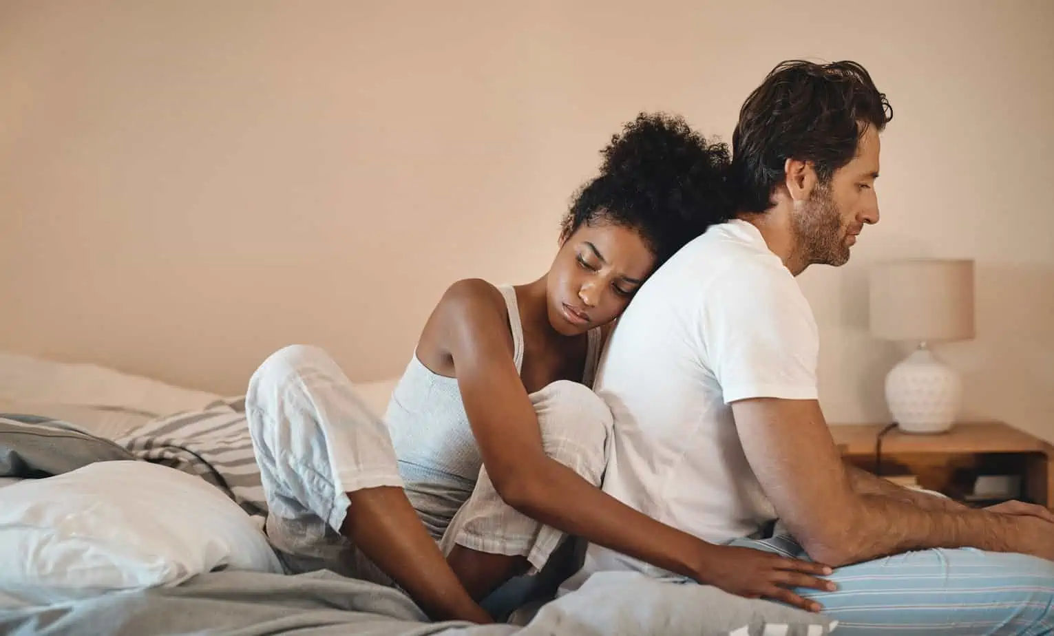 sad woman embraces distressed man on bed