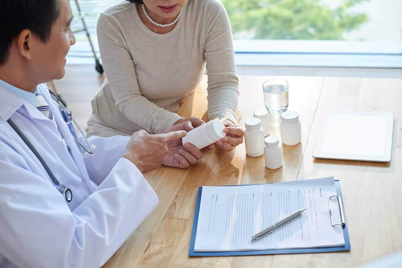 Medical Doctor reviewing bottles of unlabeled medication / pills with female client.