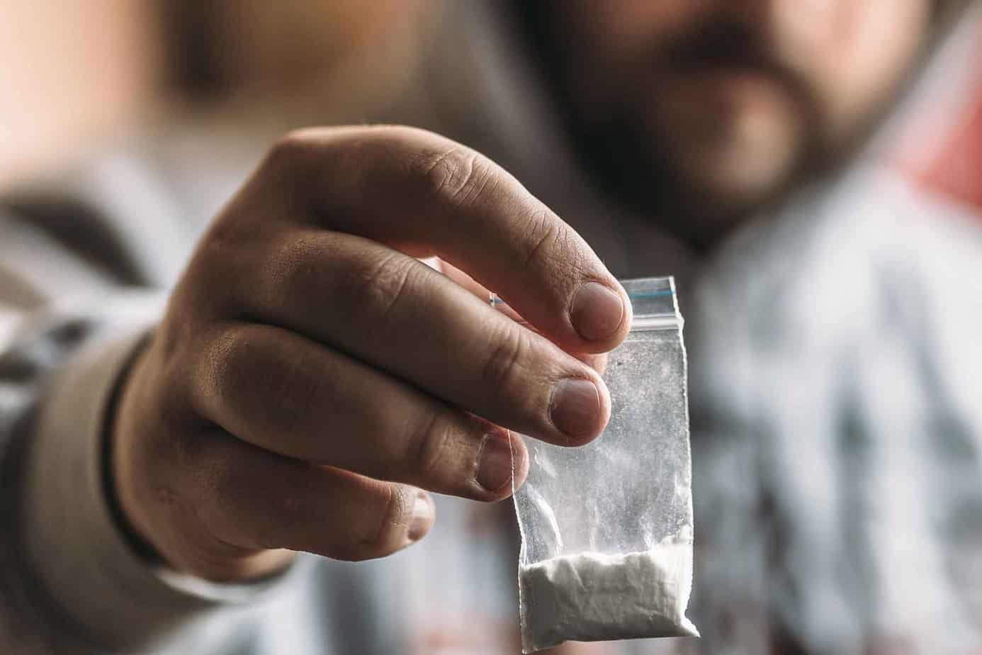 Close up of a man's hand holding a bag of white powder