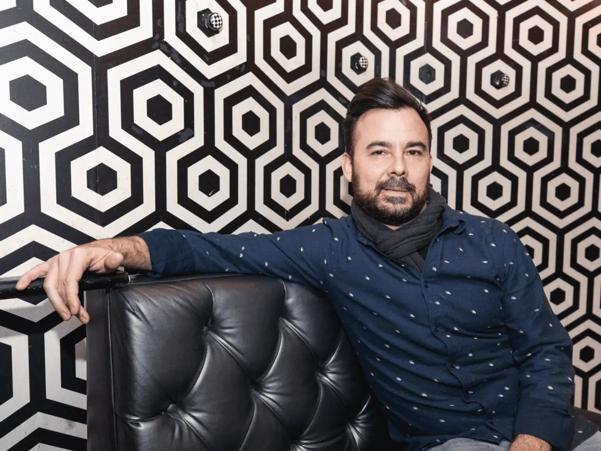 Bryan Santiago photo - Man on black couch behind tiled wallpaper