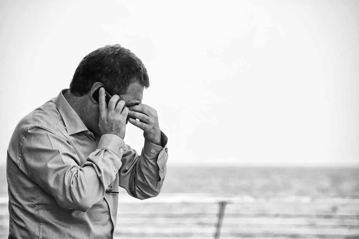 black and white photo of businessman struggling with addiction standing on pier