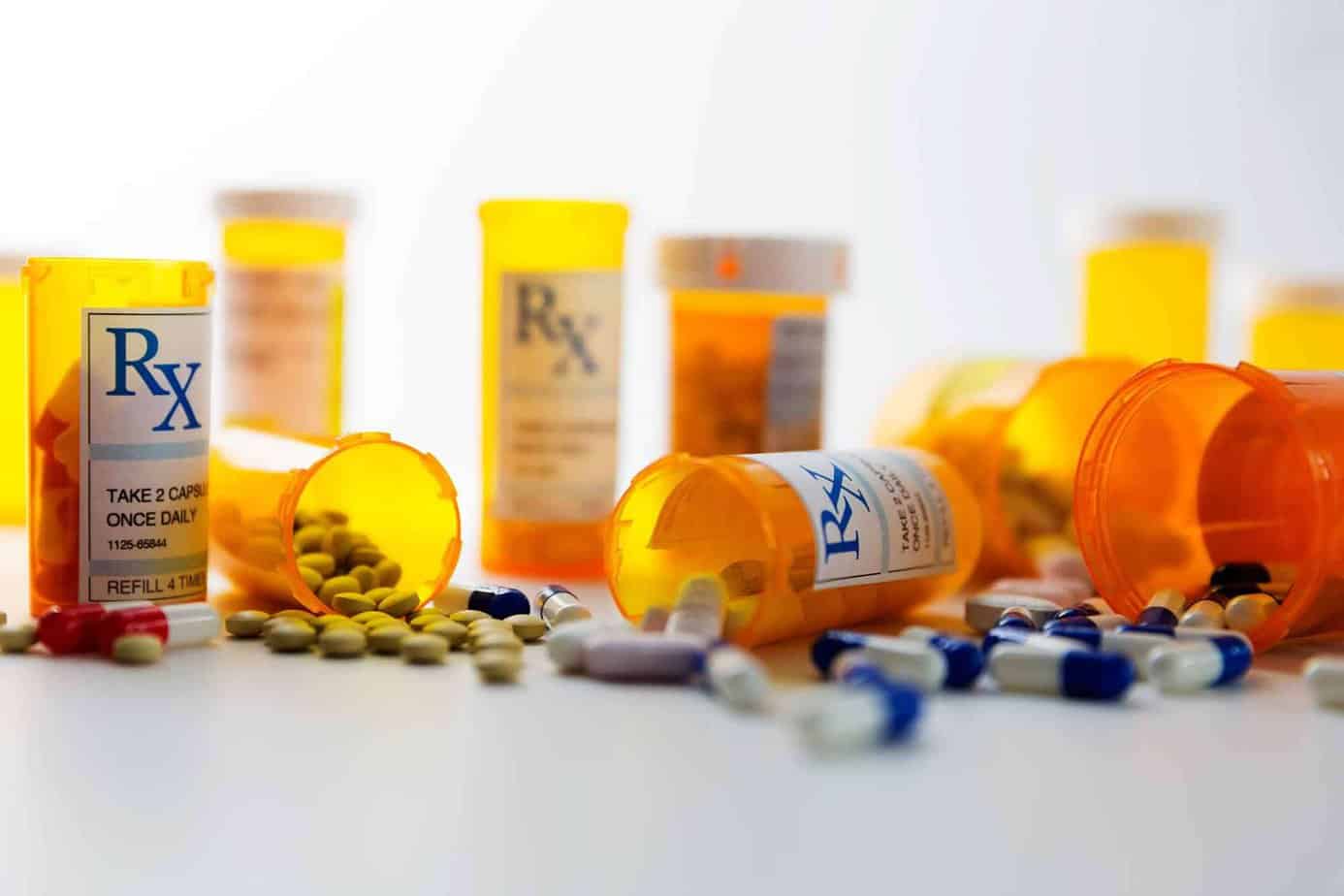Orange pill bottles with drugs scattered on a table.