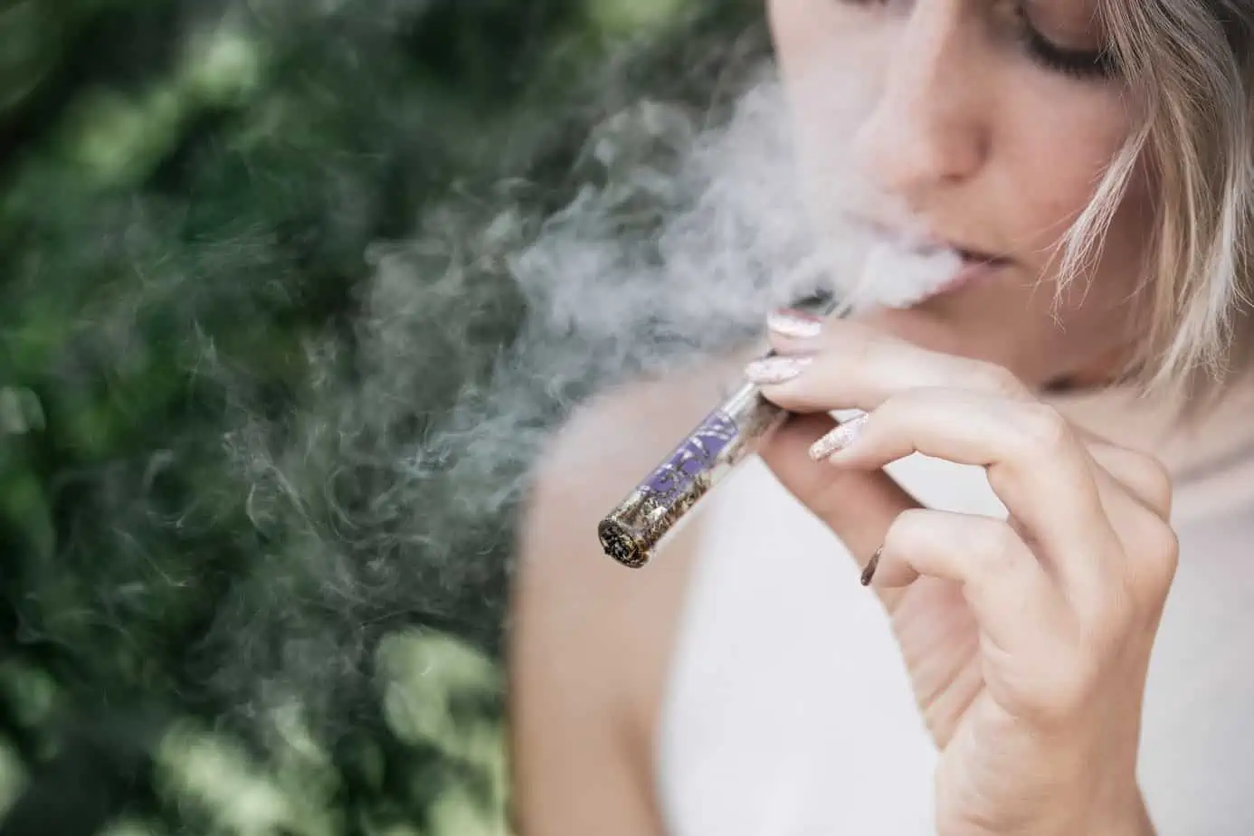 woman uses a vape pen to vape marijuana