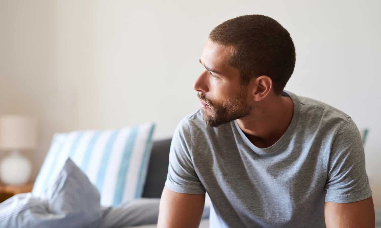 A pensive man with a goatee and close cropped haircut sits thinking