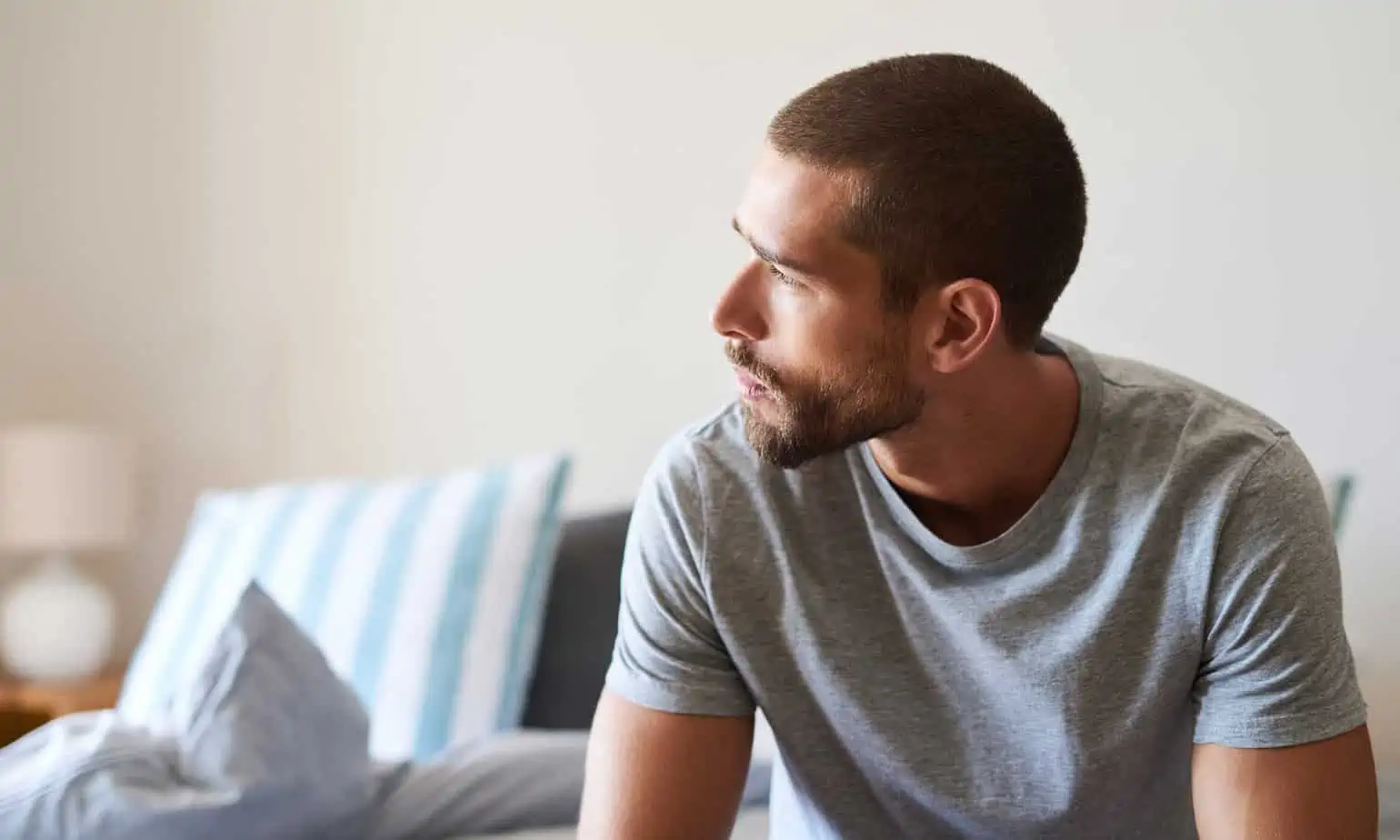 A pensive man with a goatee and close cropped haircut sits thinking