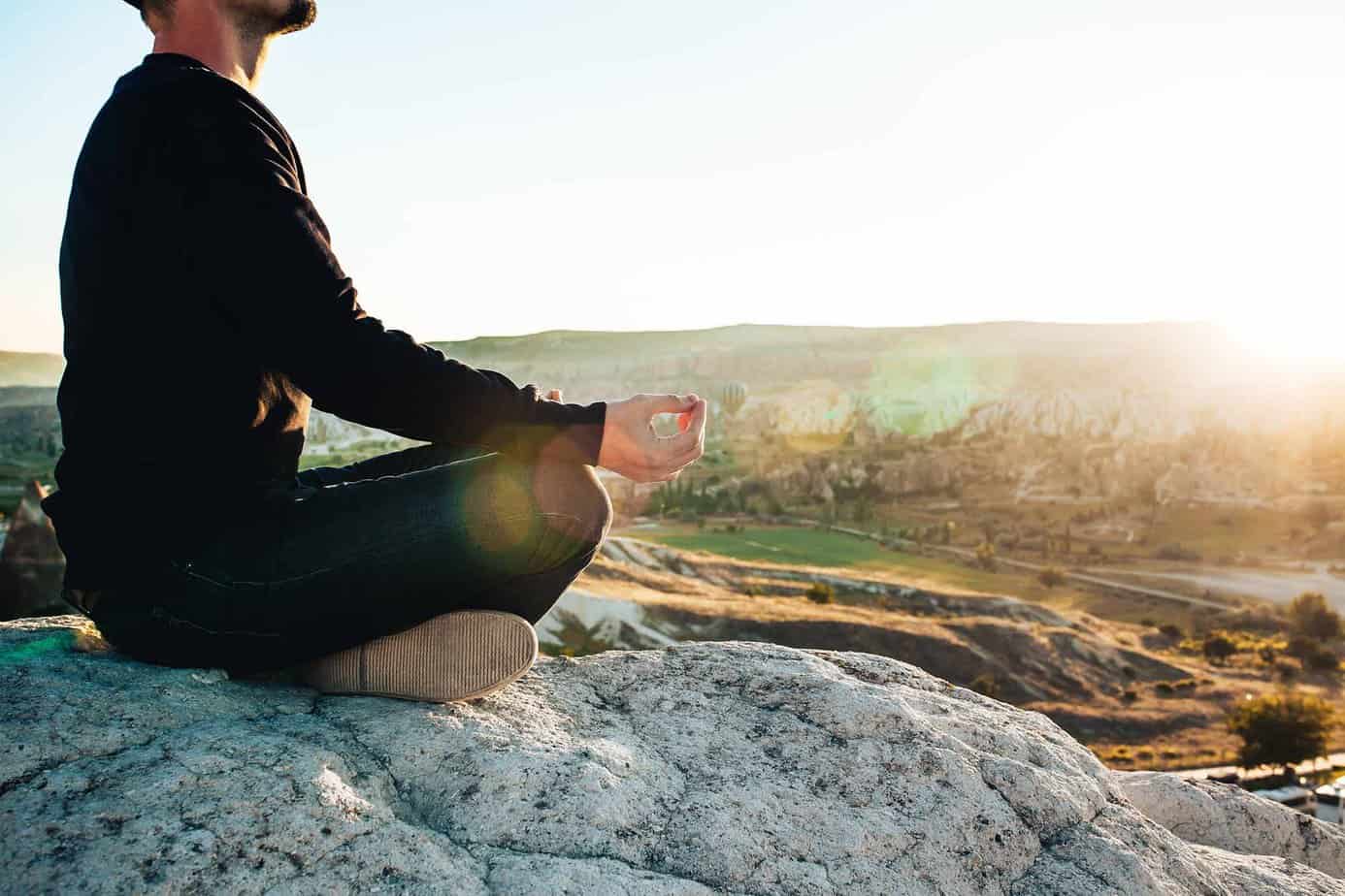 Man doing meditation on rock on mountain