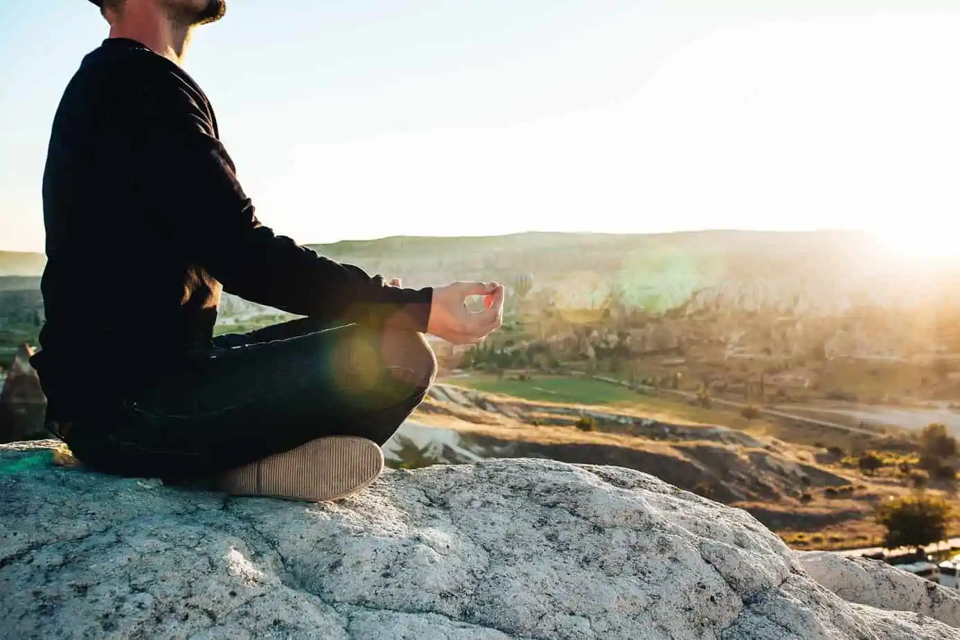 Man doing meditation on rock on mountain