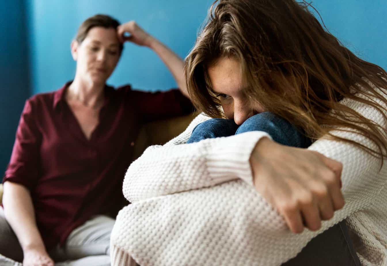 mother and daughter have tense conversation, with daughter looking upset and mother looking disappointed