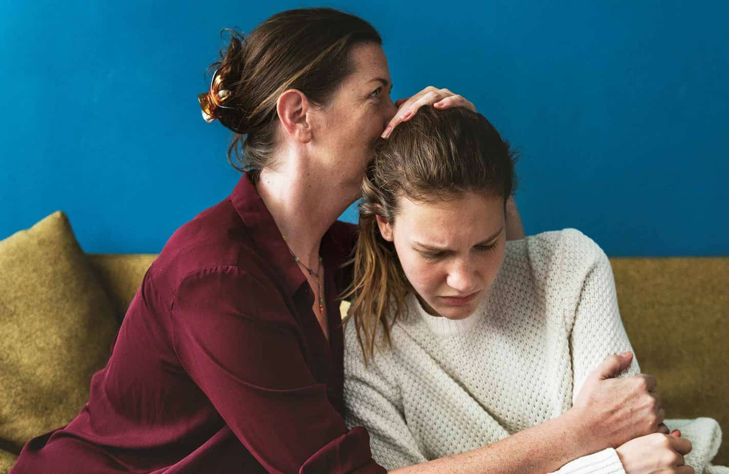 mother comforting addicted daughter by hugging her
