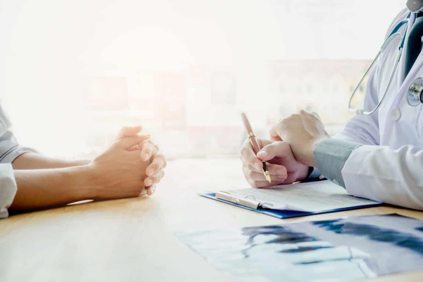 doctor holding a pencil speaking to a client and taking notes