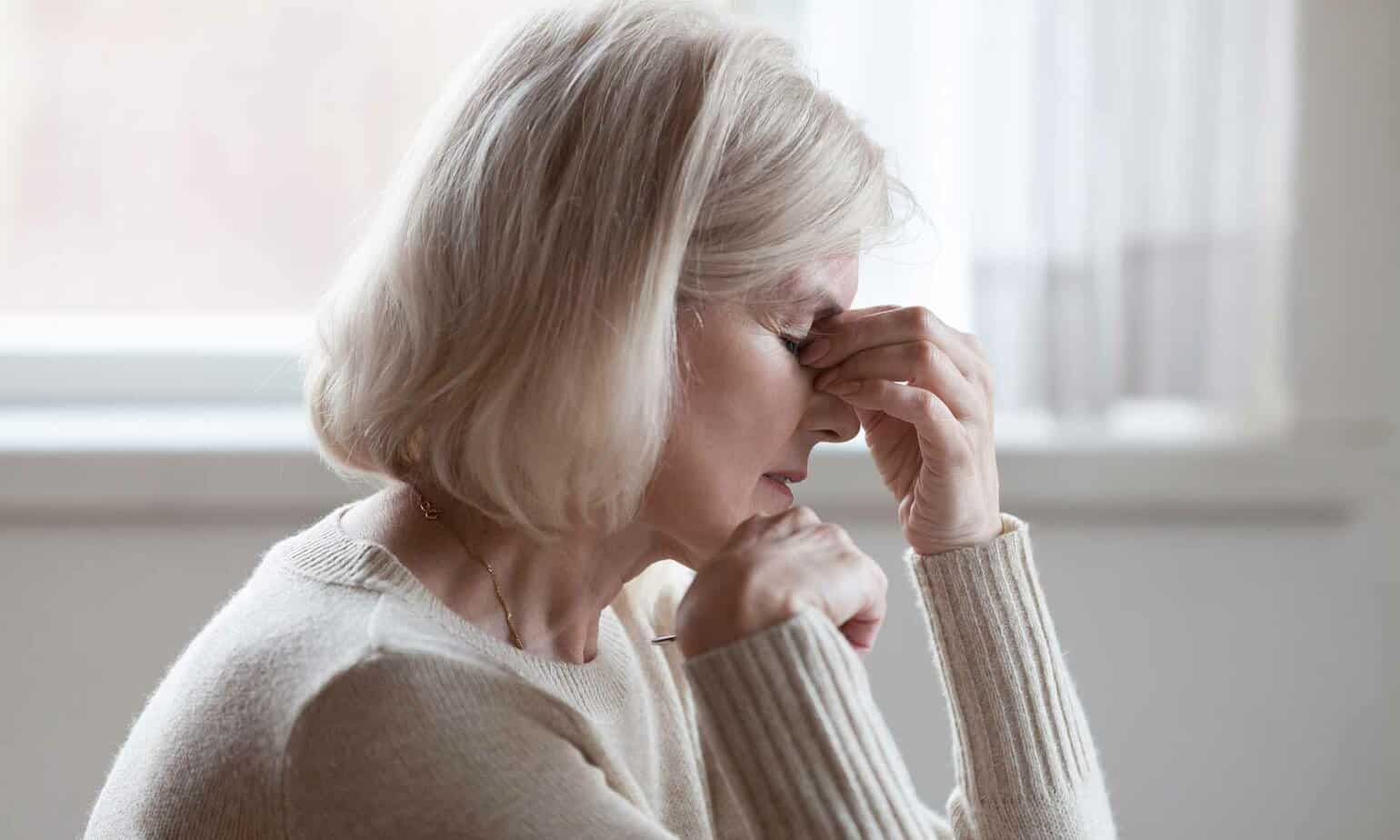 A woman holds her head as she experiences an emotional trigger