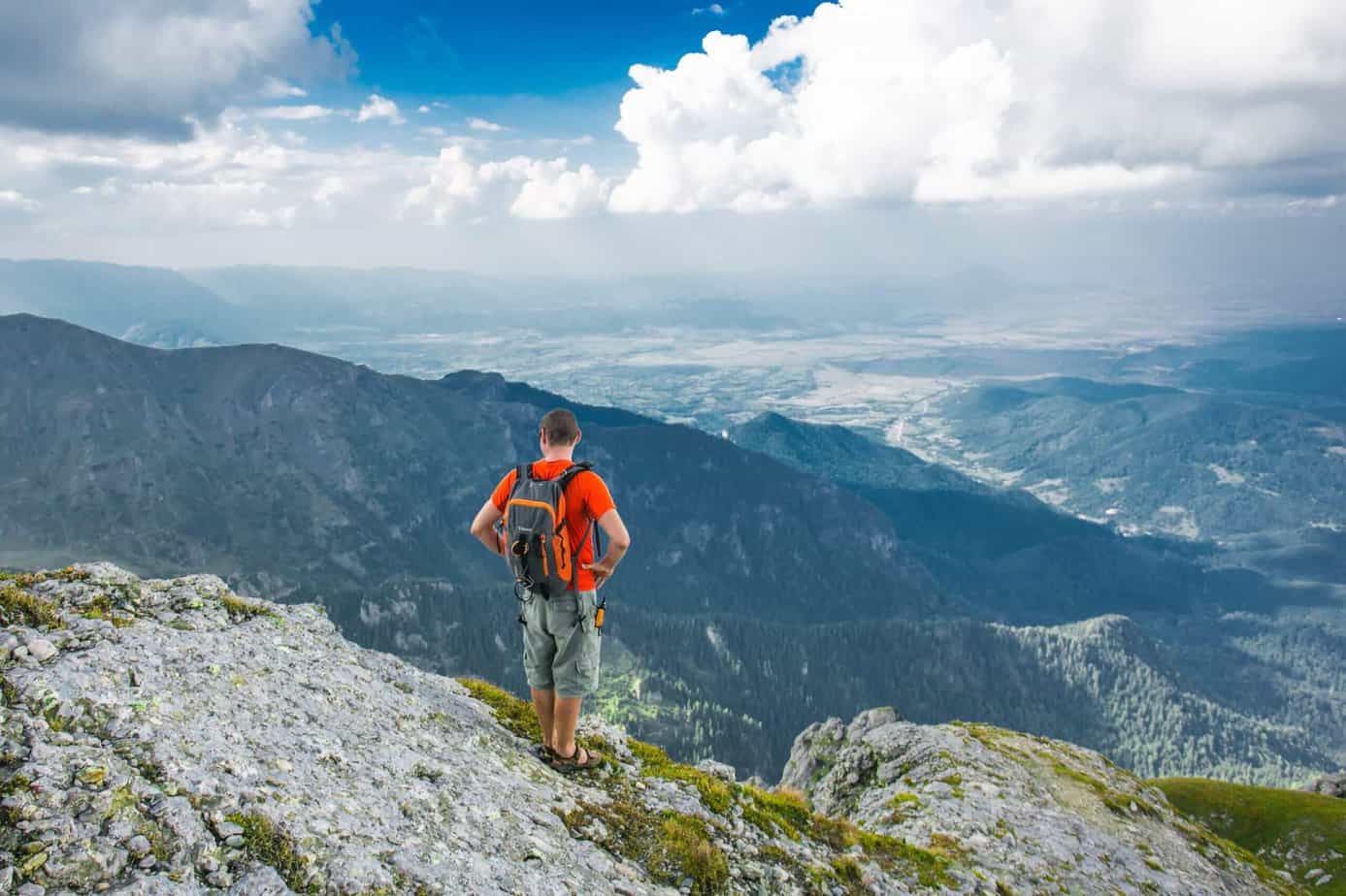 Man hiking in the mountains under blue skies.