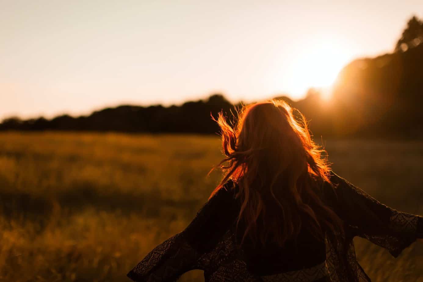 woman running carefree through field at sunset