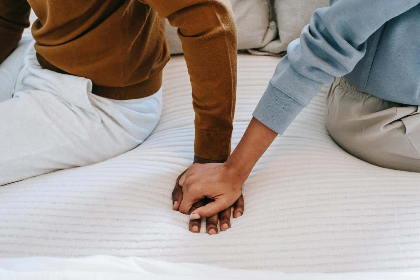 people seated on bed holding hands