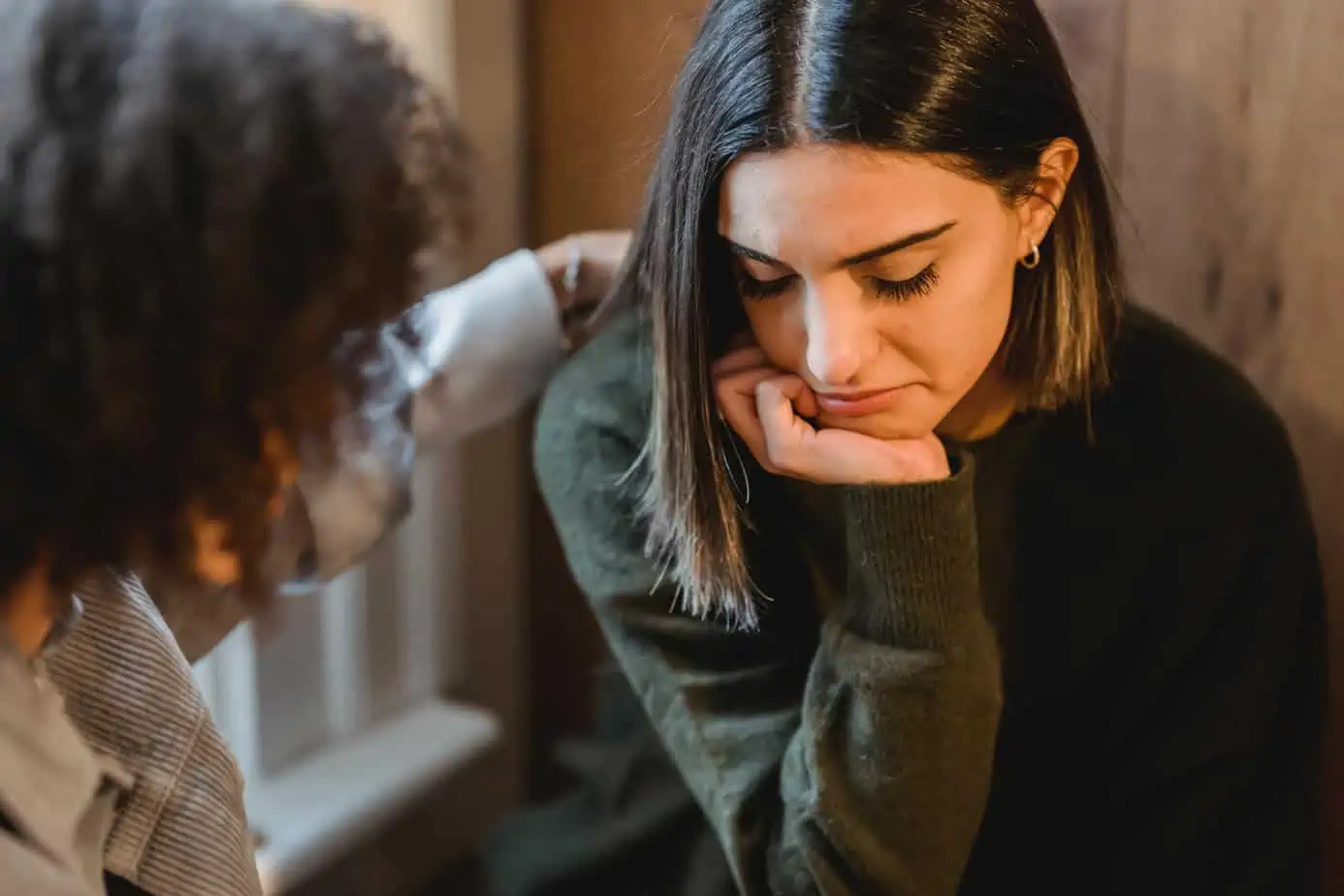 woman supporting other sad woman with head in hands