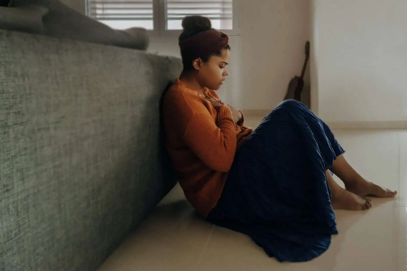 Woman experiencing survivor’s guilt clutches her hands to her chest