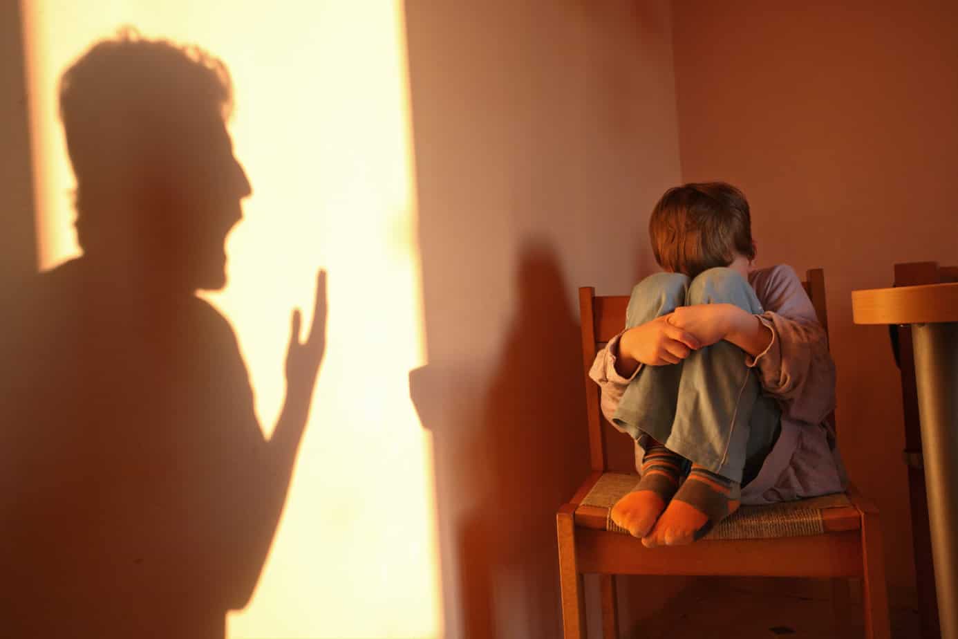 woman hides in shadows from angry, yelling man
