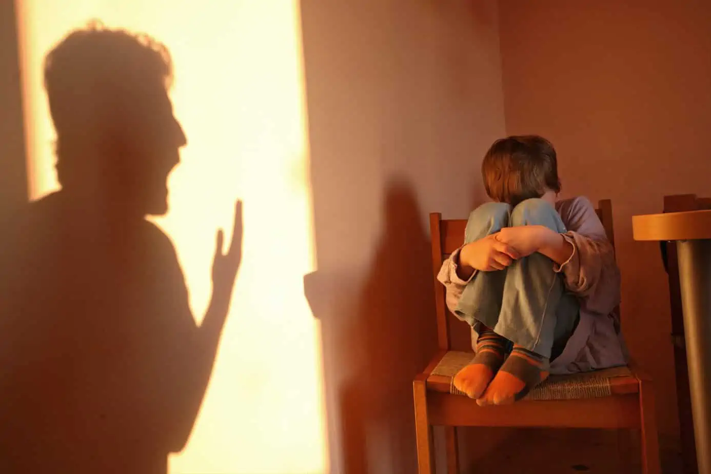 woman hides in shadows from angry, yelling man