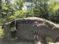 woman and child stand before rock in forest