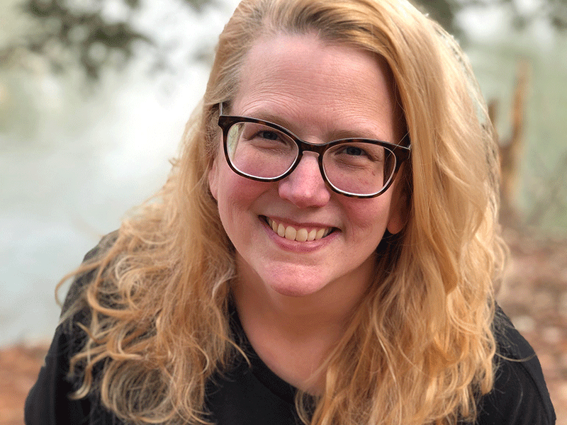 smiling woman in glasses poses for outdoor portrait