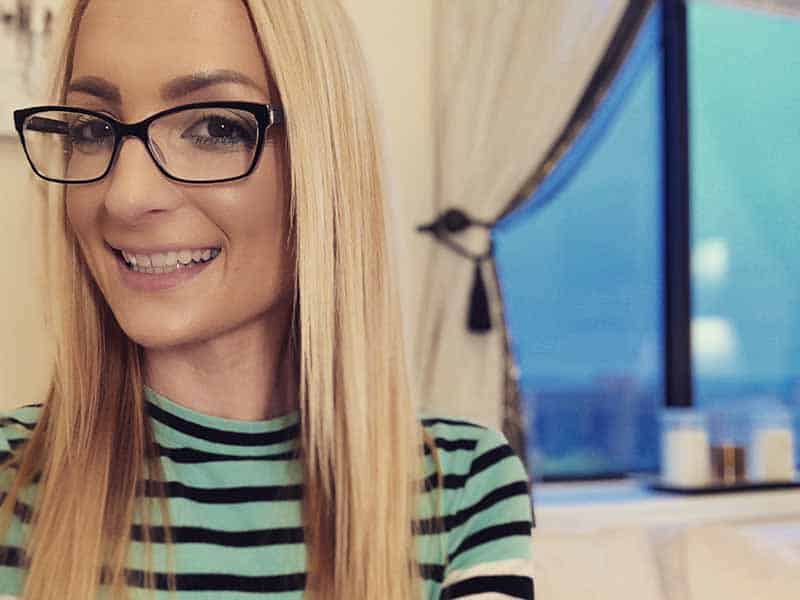 woman in glasses smiling by window