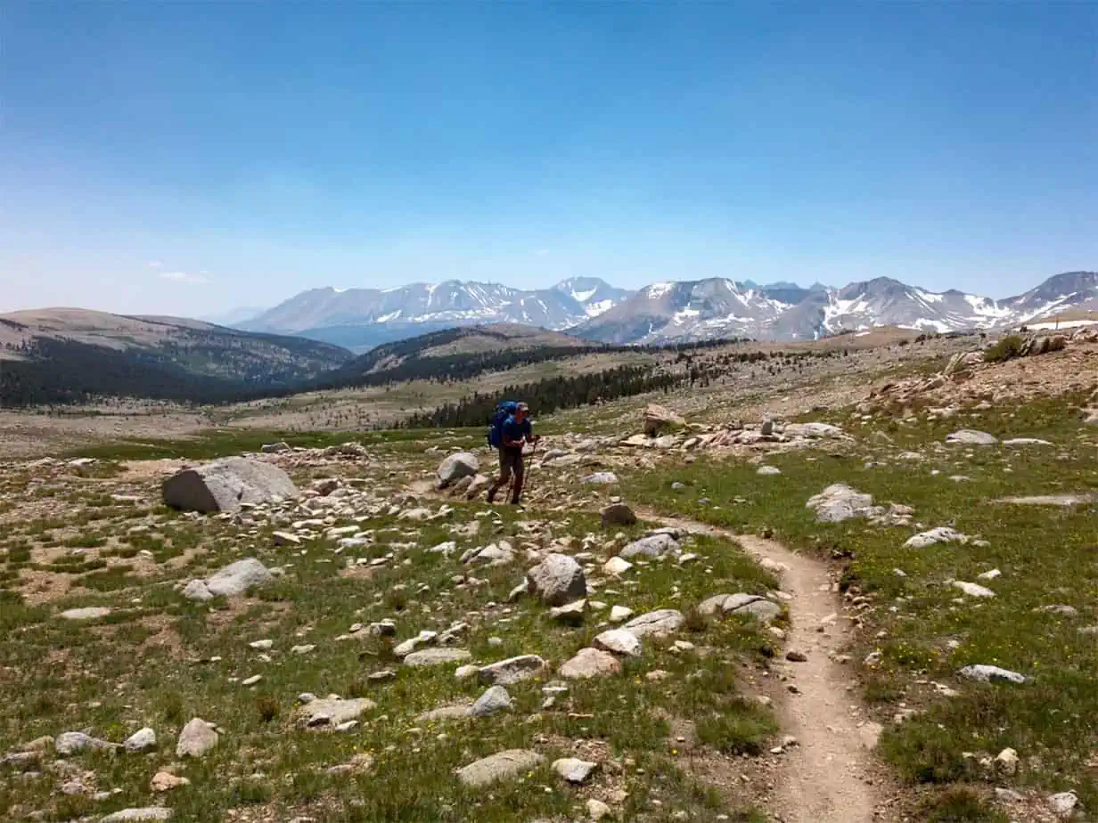 man hiking on barren, rocky trail in mountainous scenery