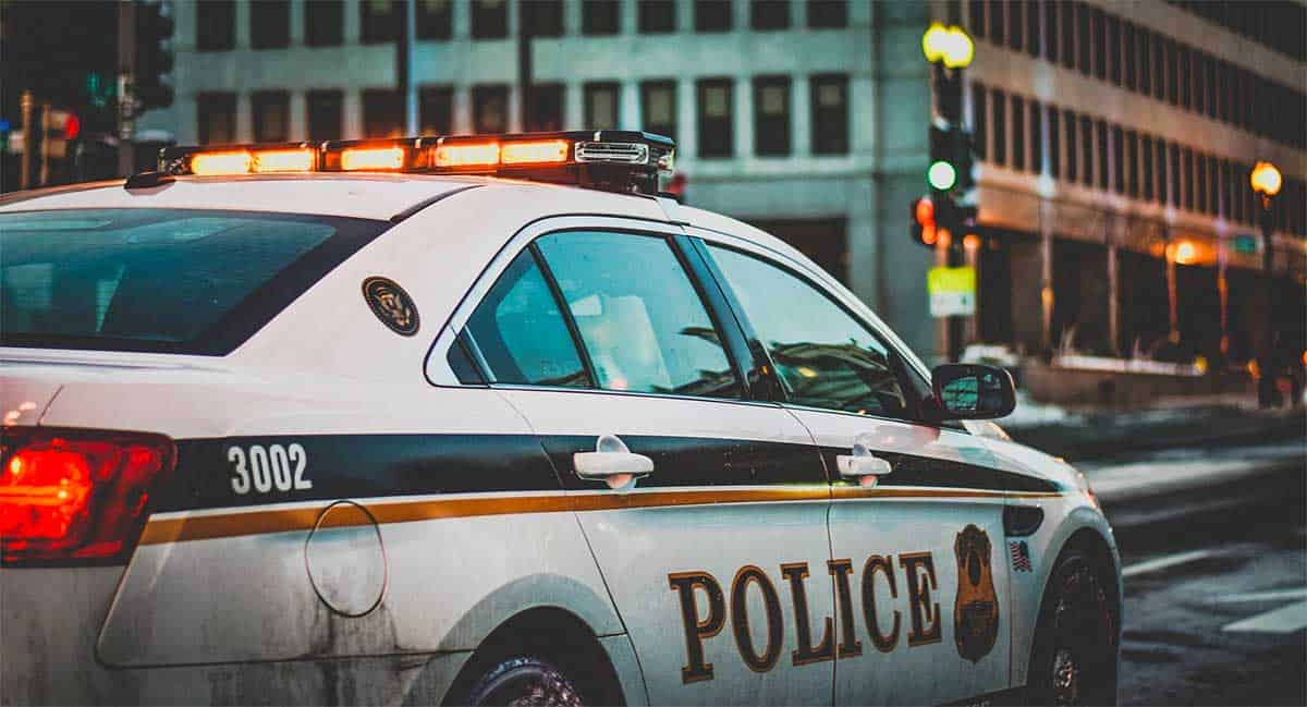 police car stopped at a traffic light in a busy city