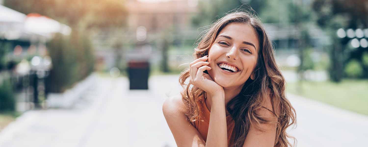 smiling girl with head on hand posing in street