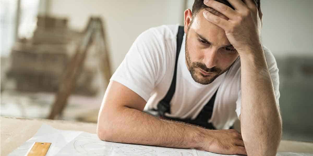 stressed out man with head in hands leans on table