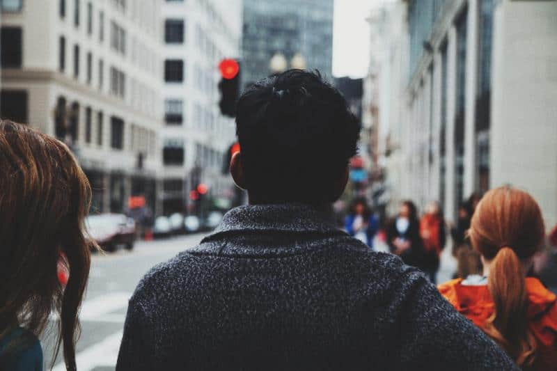 man stopped at crosswalk in busy city