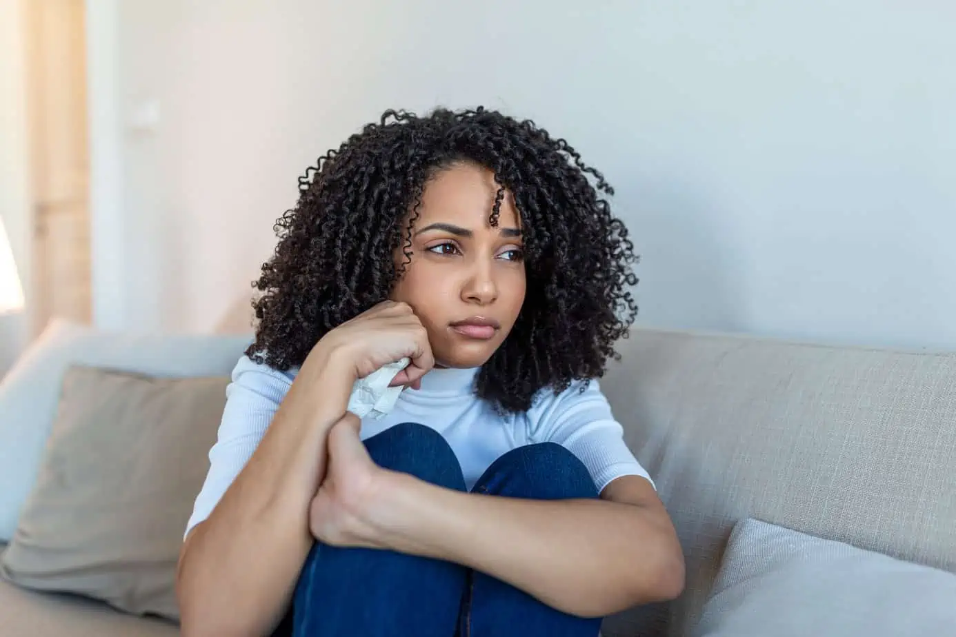 woman sitting on couch occupied with negative thoughts