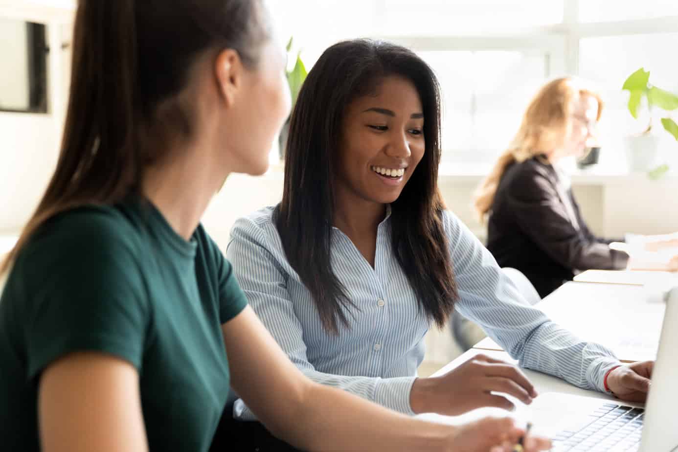 2 professional smiling at work over a computer