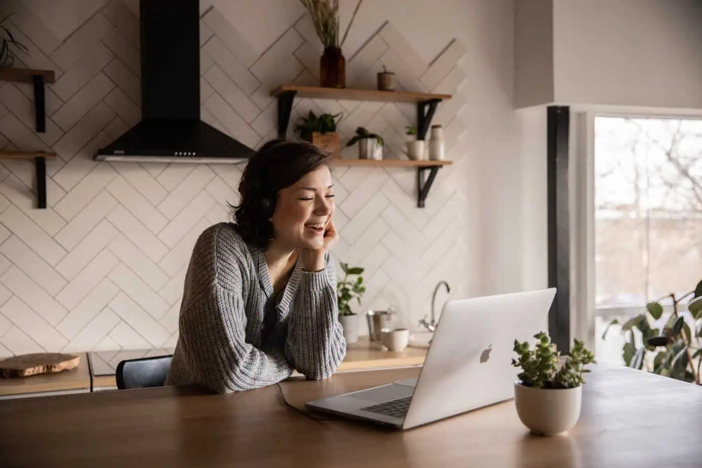 Happy woman using a laptop in her kitchen. Outpatient Addiction Treatment Service from Mountainside.