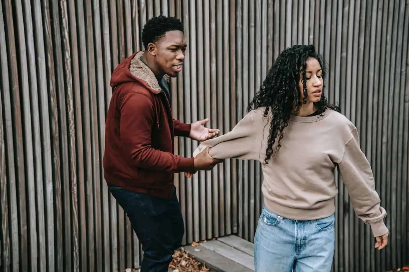 A young man is holding onto a young woman trying to walk away