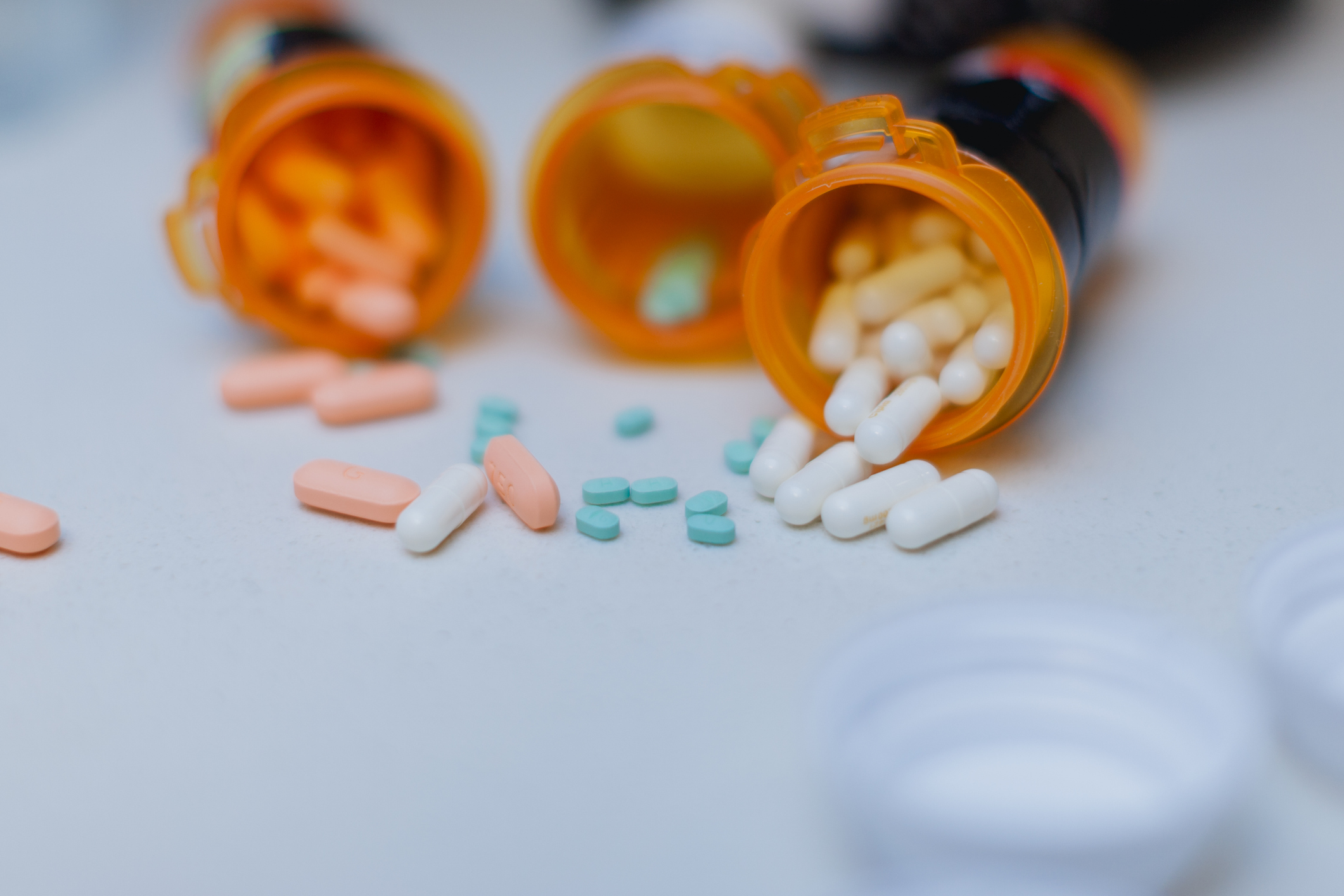 Three pill bottles all on their sides will pills spilling out of them.