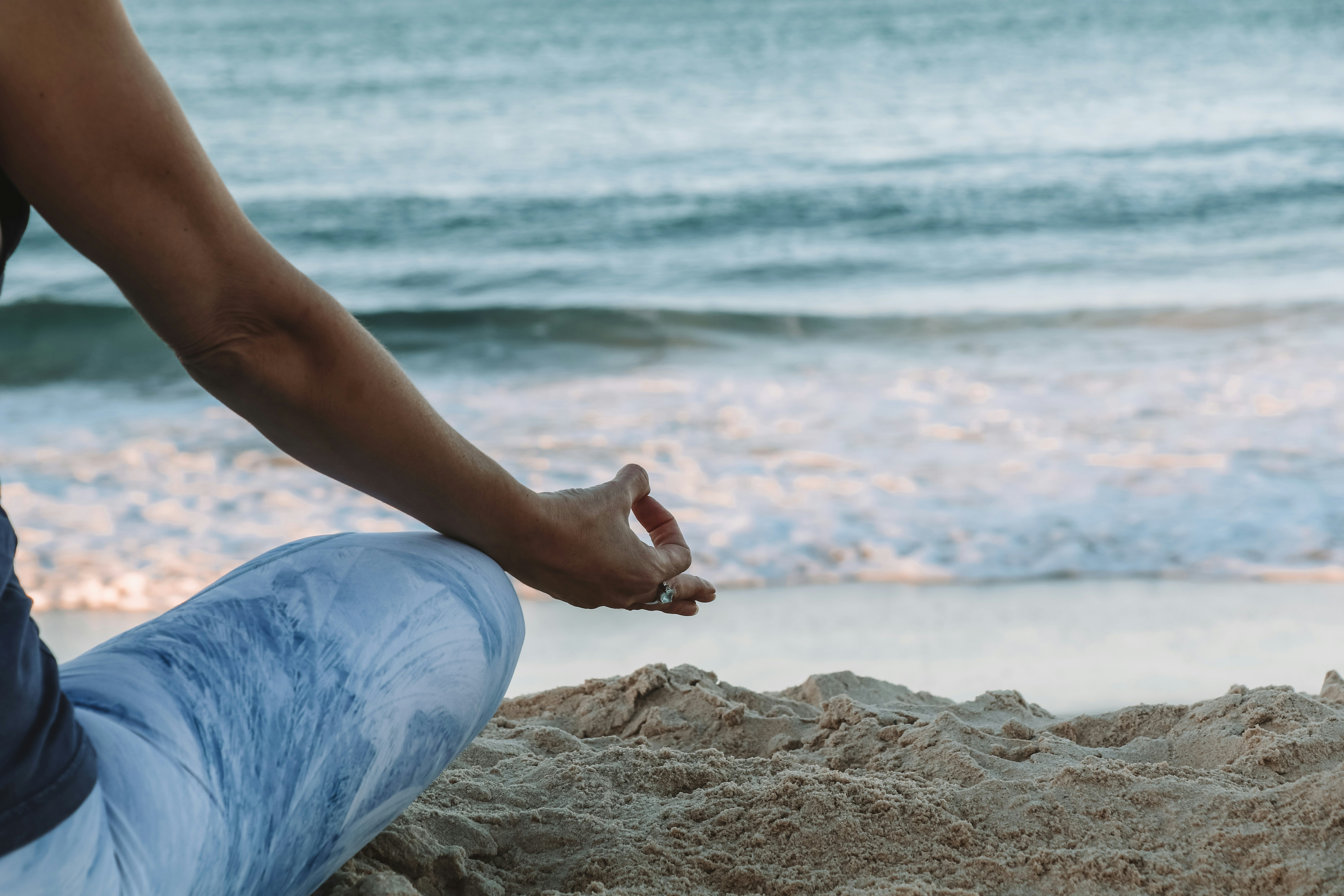 A woman practices yoga and meditation on the beach as part of her mindful routine