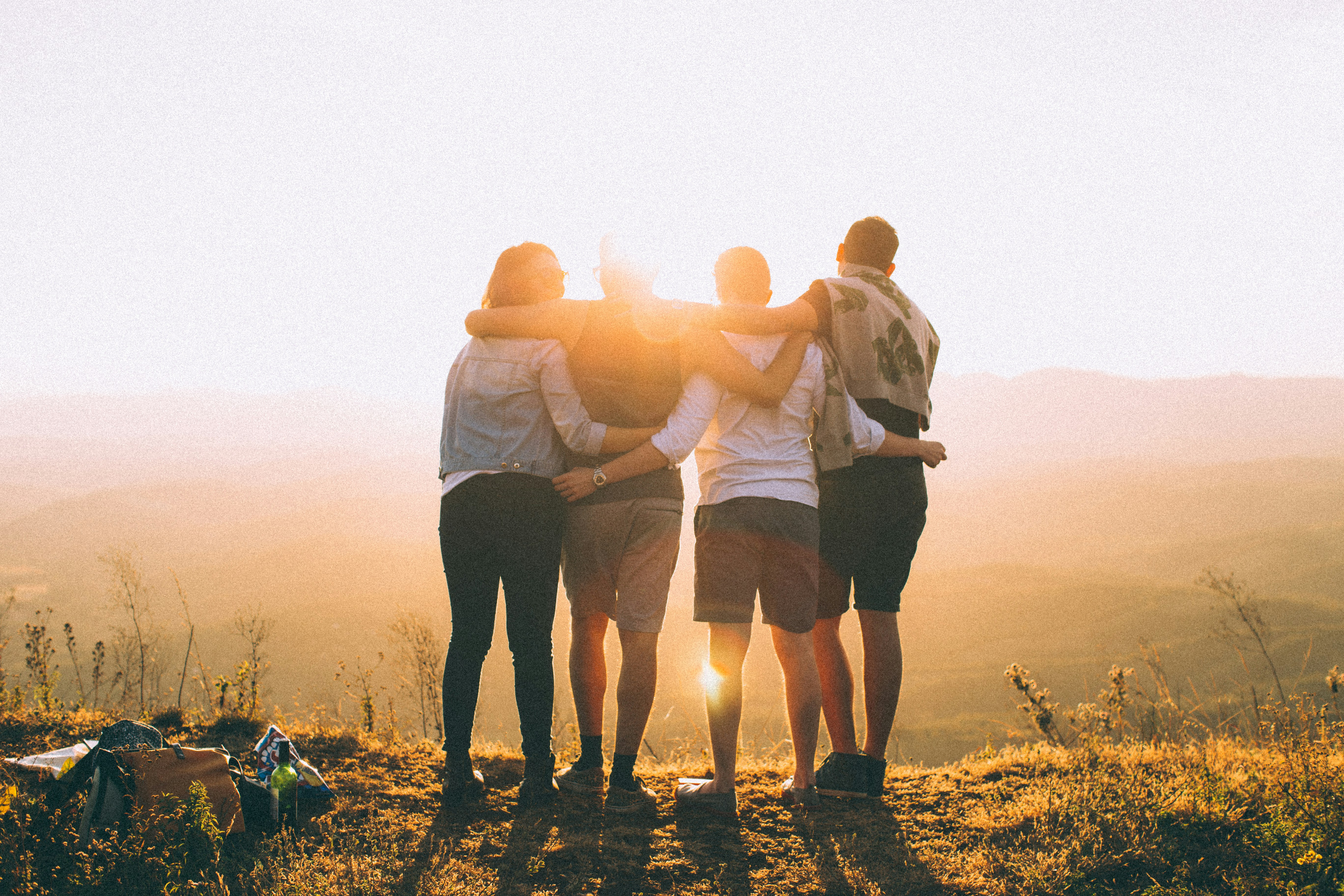 a group of four hikers standing on a mountain practicing harm reduction